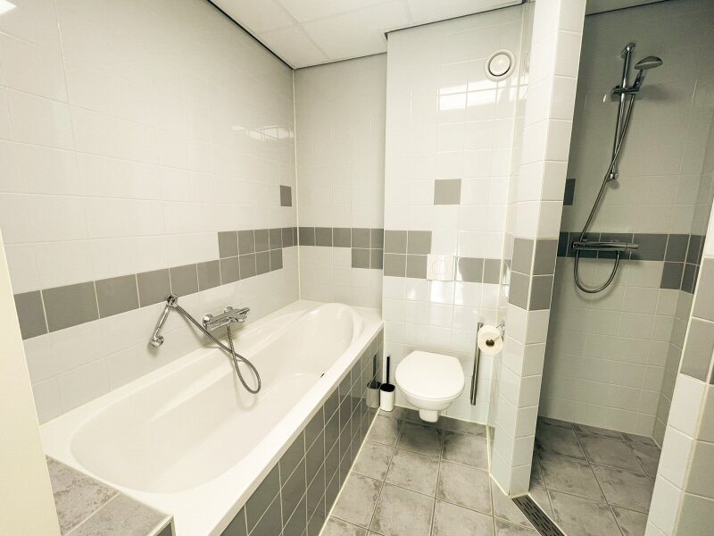 Badkamer met bad en aparte douche in een kamer van Donia Huys op Vlieland.