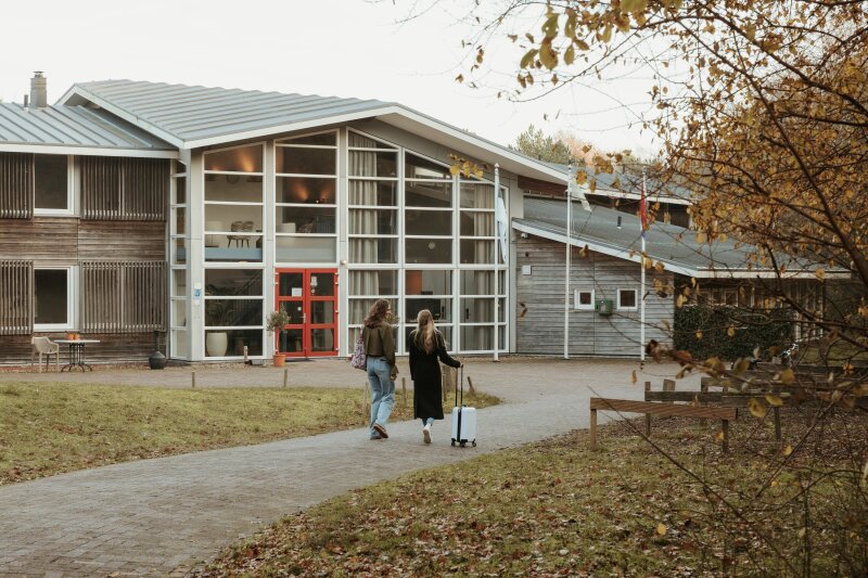Twee gasten lopen met koffer over het pad naar de ingang van Donia Huys op Vlieland.