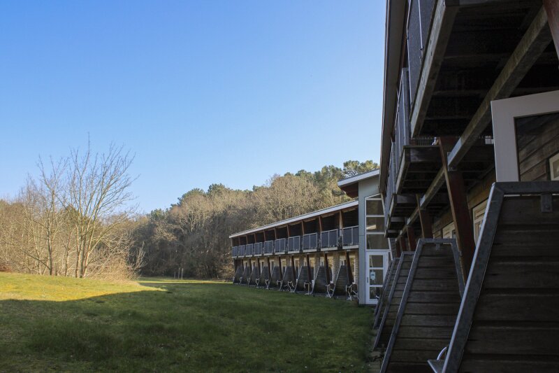 Buitenaanzicht van het hotel met balkons en terrassen grenzend aan tuin en bos bij Donia Huys Vlieland.