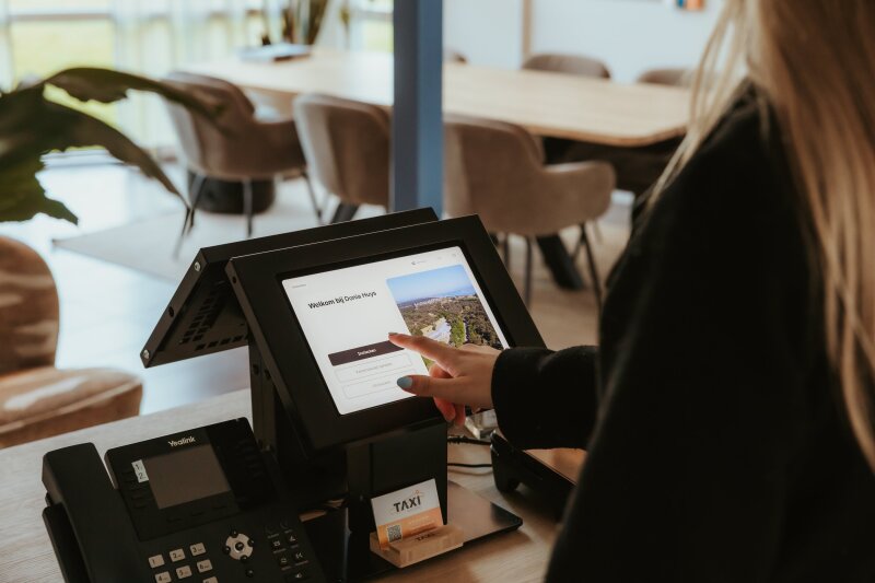 Gast gebruikt de self check-in zuil bij aankomst in Donia Huys op Vlieland.