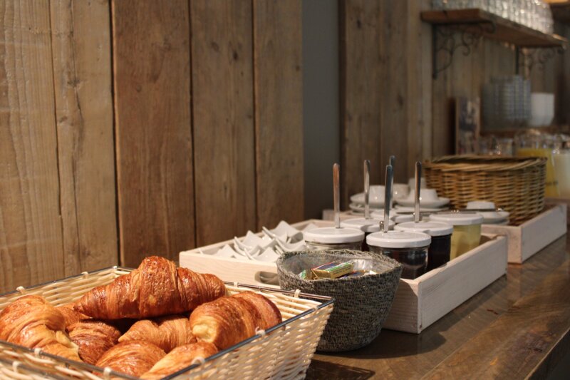 Ontbijtbuffet met croissants, jam en bestek bij Donia Huys.