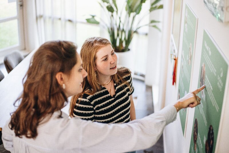 “gasten-binnen-bij-donia-huys-bekijken-informatiebord-en-wijzen-naar-activiteiten.