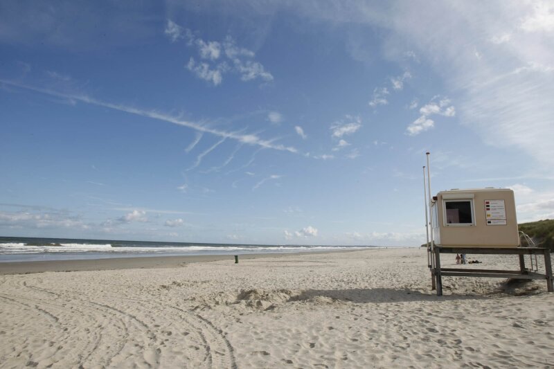 strand-op-vlieland-met-zee-blauwe-lucht-en-een-strandwachtpost-in-het-zand.